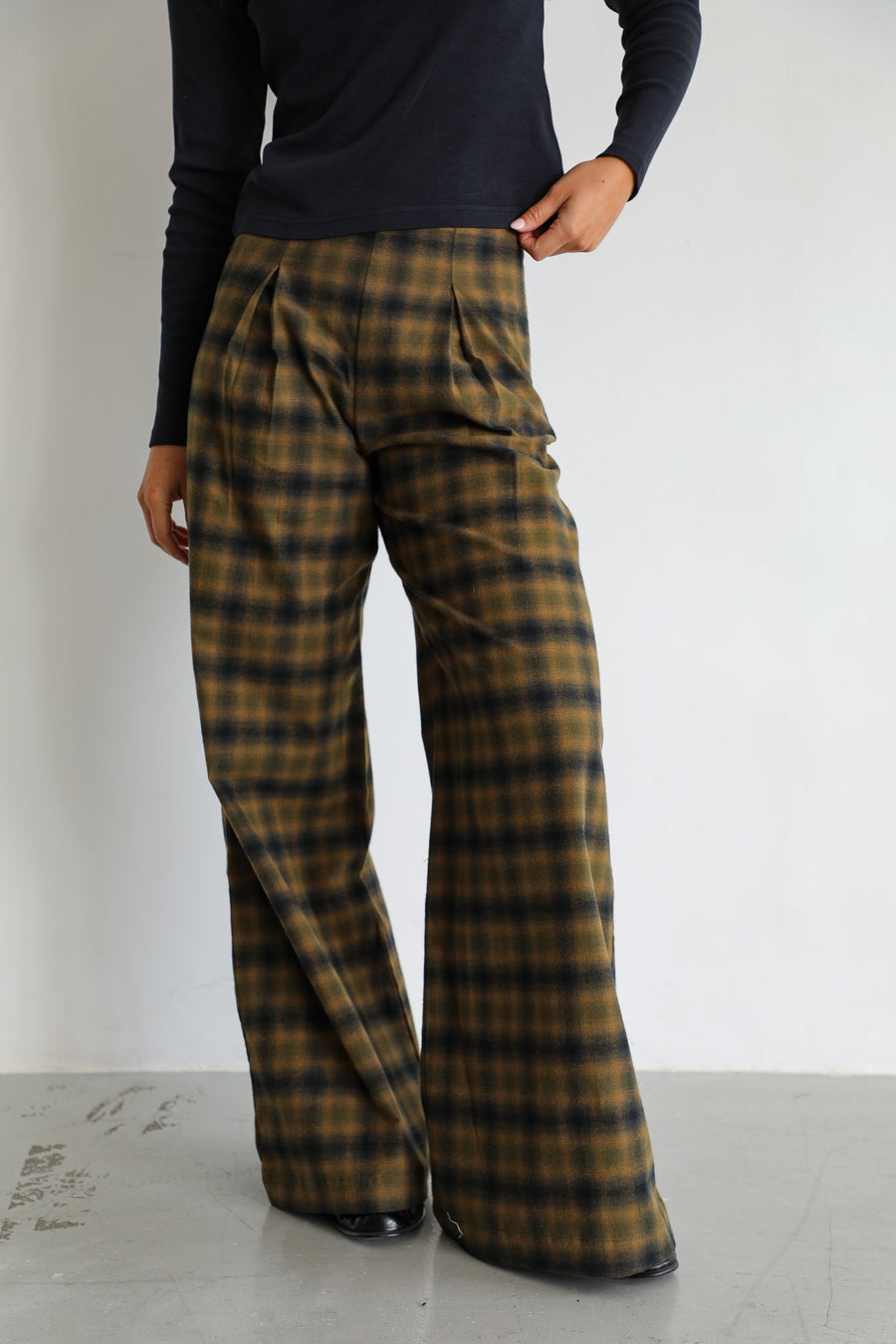 Detail of the Square Detail Pants Grey: 100% cotton wide-leg trousers with front pleats and a grey and brown check, worn with the navy long-sleeve organic cotton T-shirt.