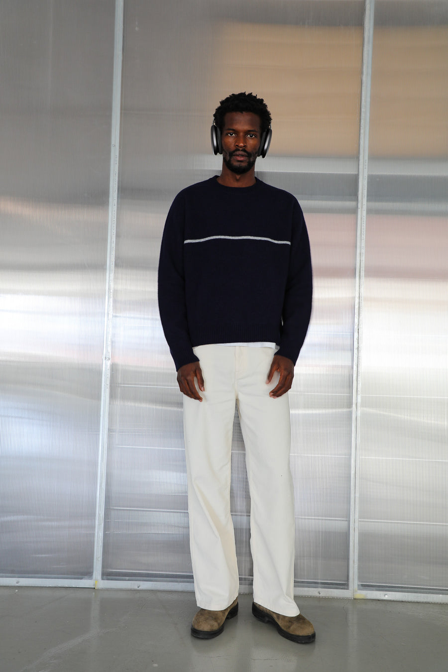 Full-length front view of the model in the Line Round Knit Sweater Dark Blue, a 100% wool knit with round neckline and a contrast white line across the chest, worn with the Corduroy Wide Comfy Pants White, wide-leg 100% cotton corduroy trousers.